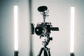 A young videographer setting up a camera with lighting equipment in a cozy studio space.