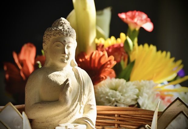 A serene Buddha statue beside a rustic basket filled with freshly baked cinnamon rolls and a wheat stalk.