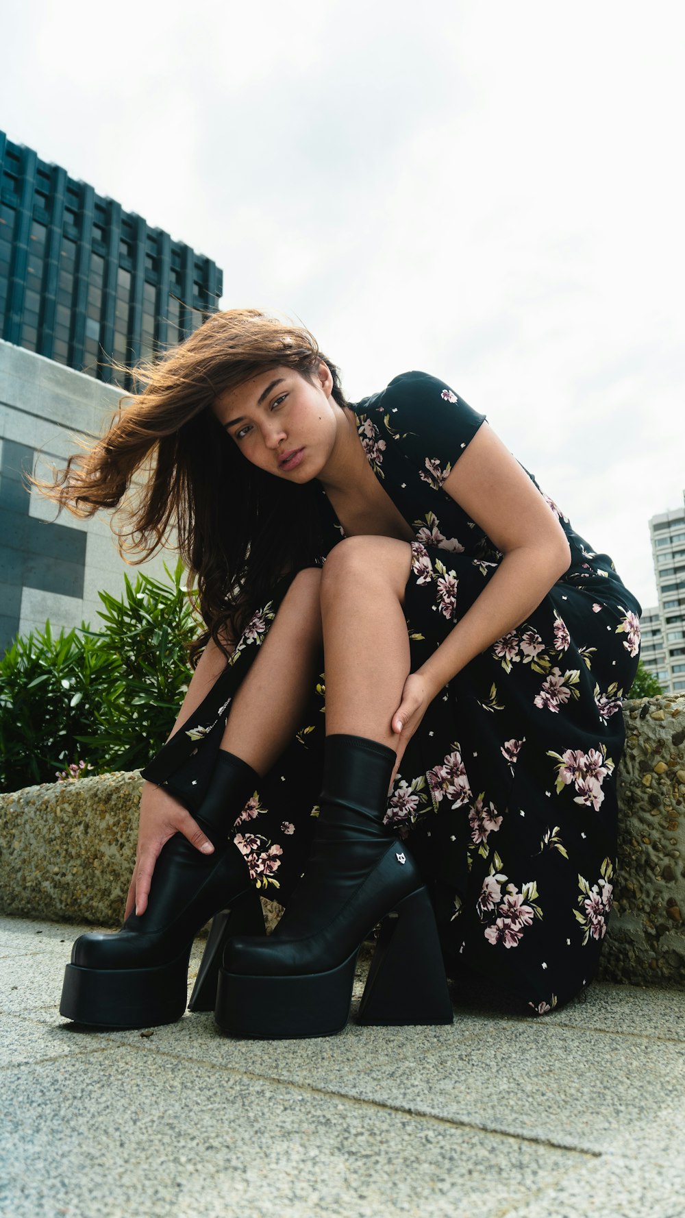 a woman sitting on the ground wearing black boots