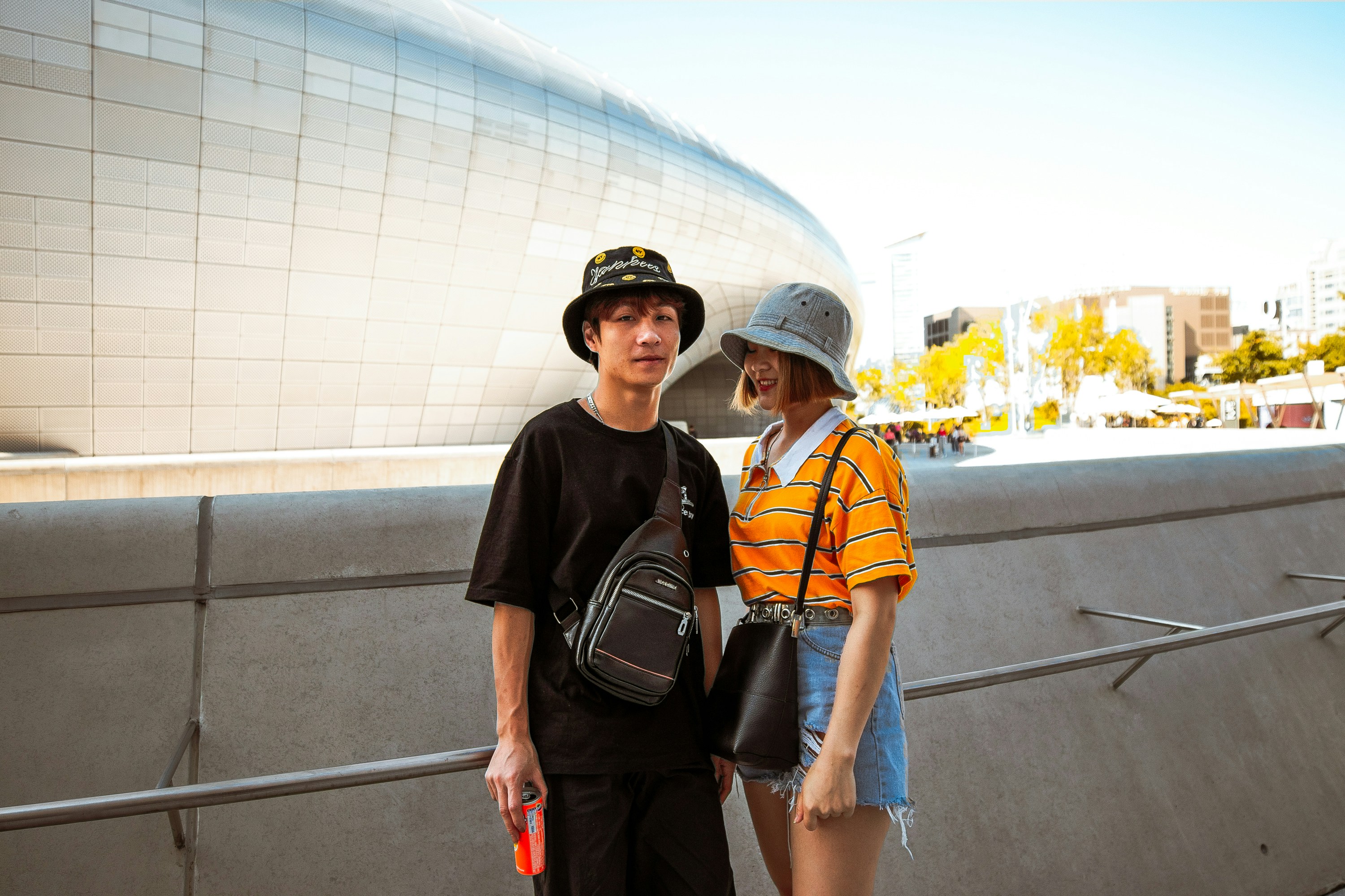 Streetwear Boy & girl outside of futuristic Zaha Hadid architecture Dongdaedum Design Plaza Seoul, South Korea