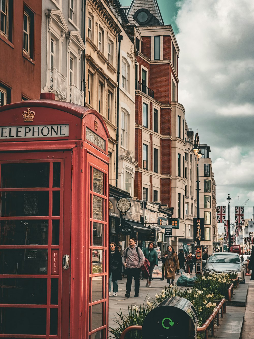 a red telephone booth sitting on the side of a road