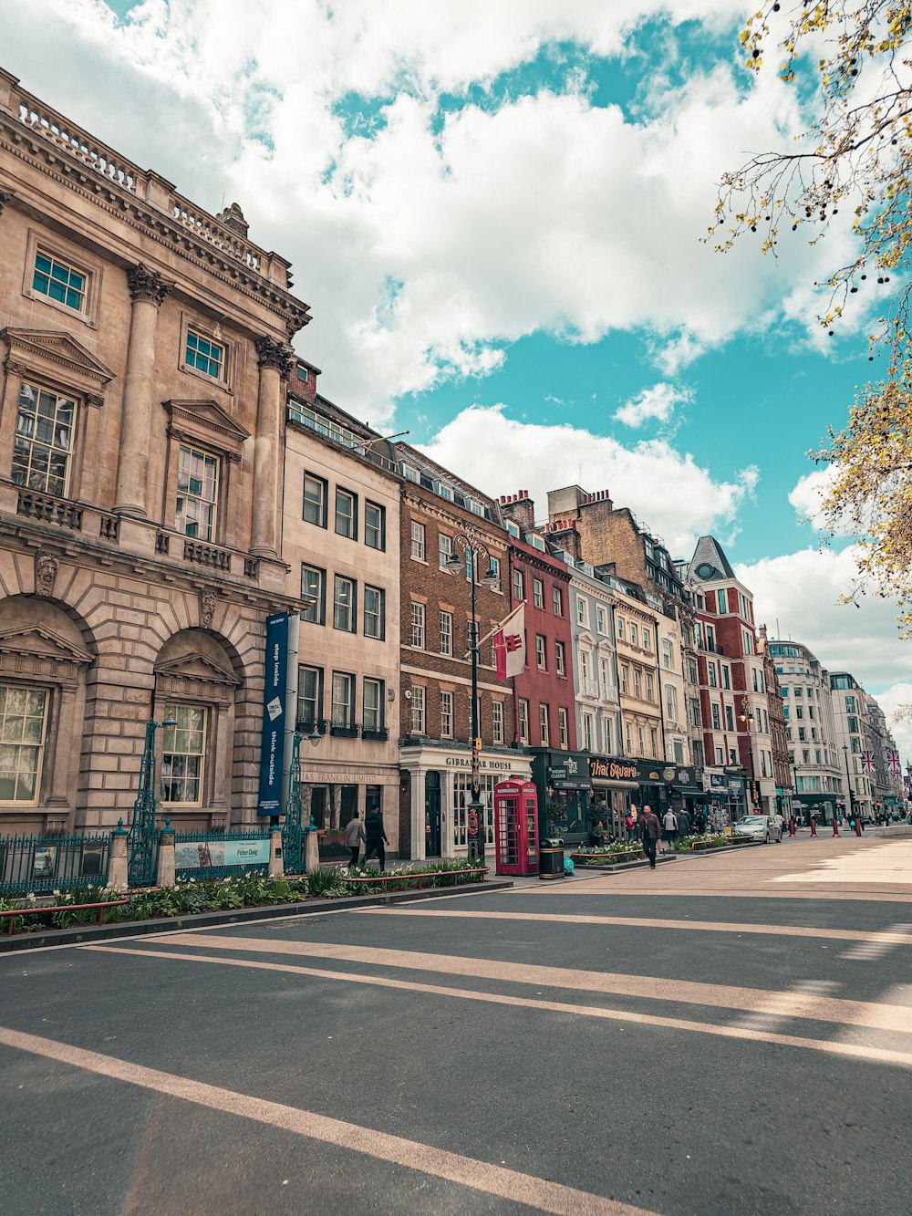 Eine Stadtstraße, gesäumt von hohen Gebäuden unter einem bewölkten blauen Himmel