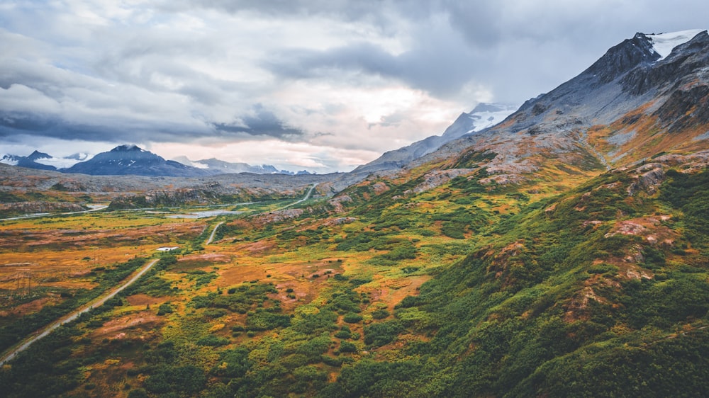 uma vista panorâmica de uma cordilheira com uma estrada sinuosa em primeiro plano