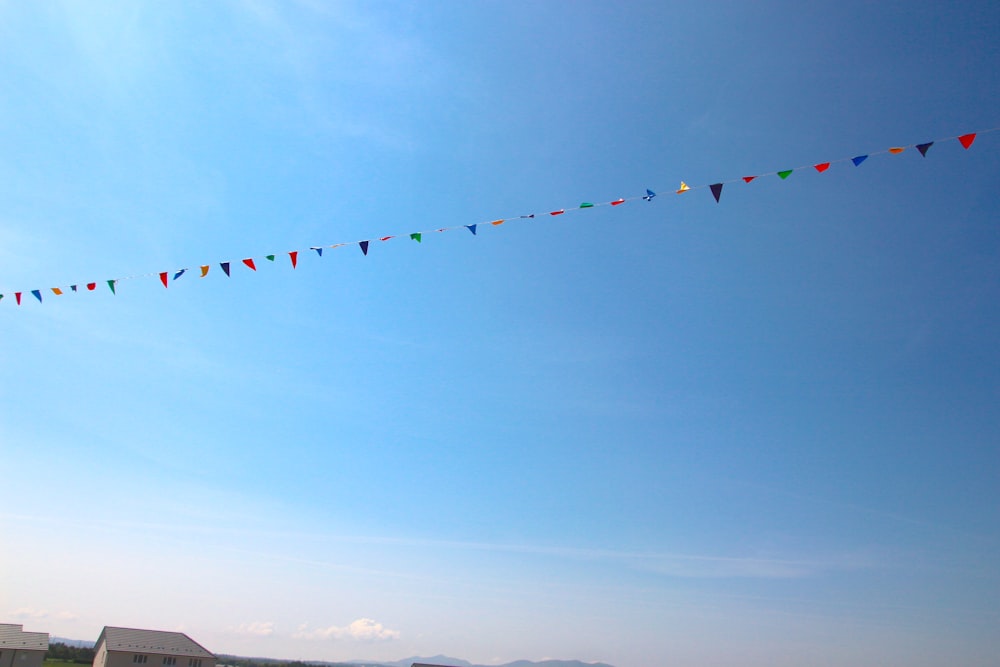 a group of people flying kites in a blue sky