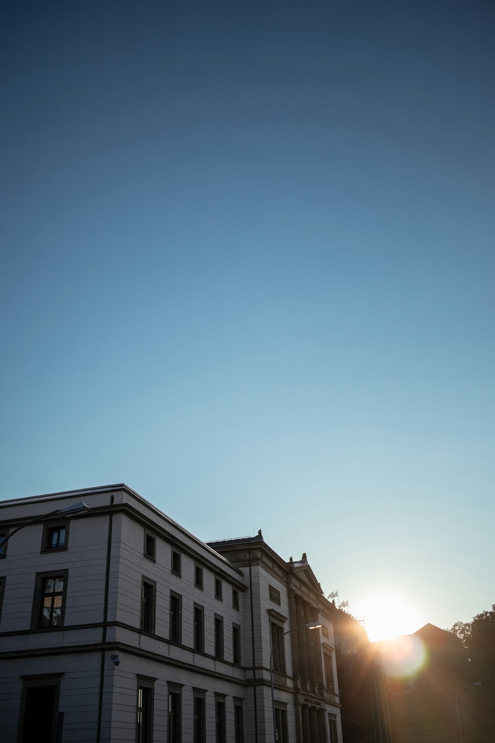 the sun is setting behind a large building