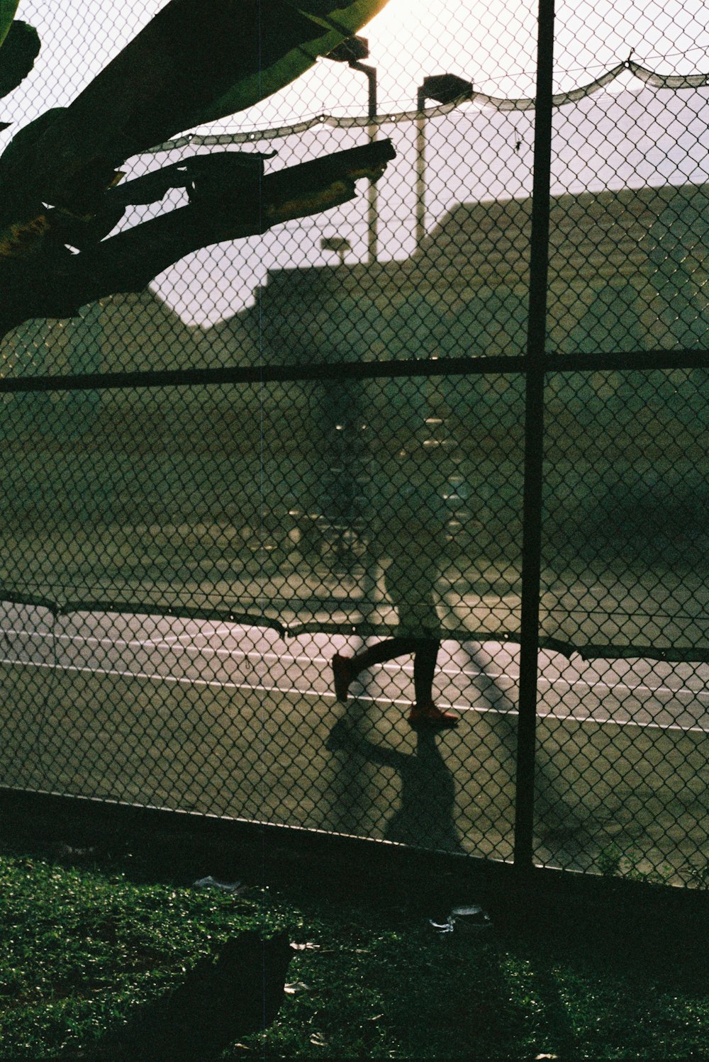 a man riding a skateboard past a tall fence