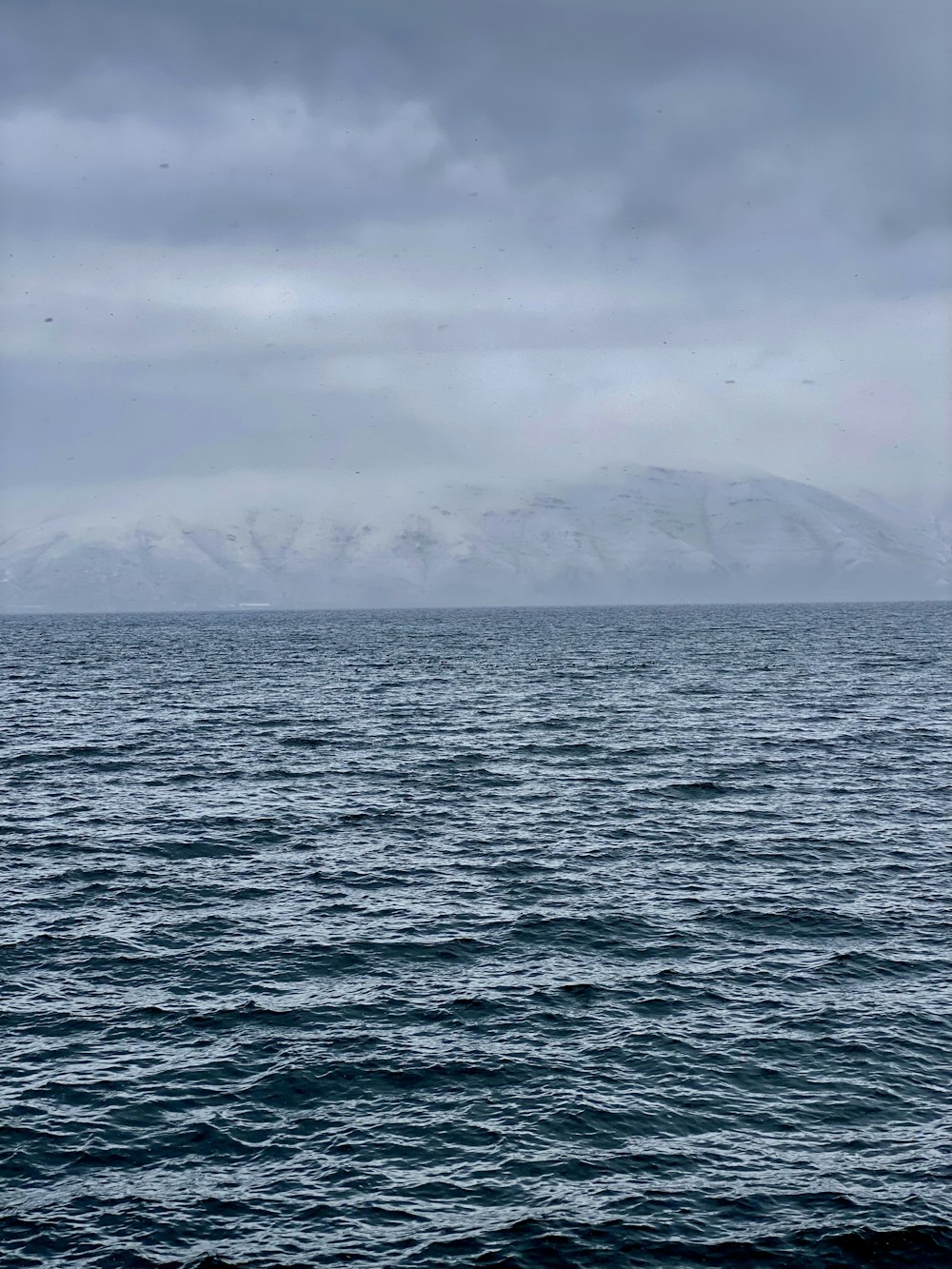 ein großes Gewässer mit Bergen im Hintergrund