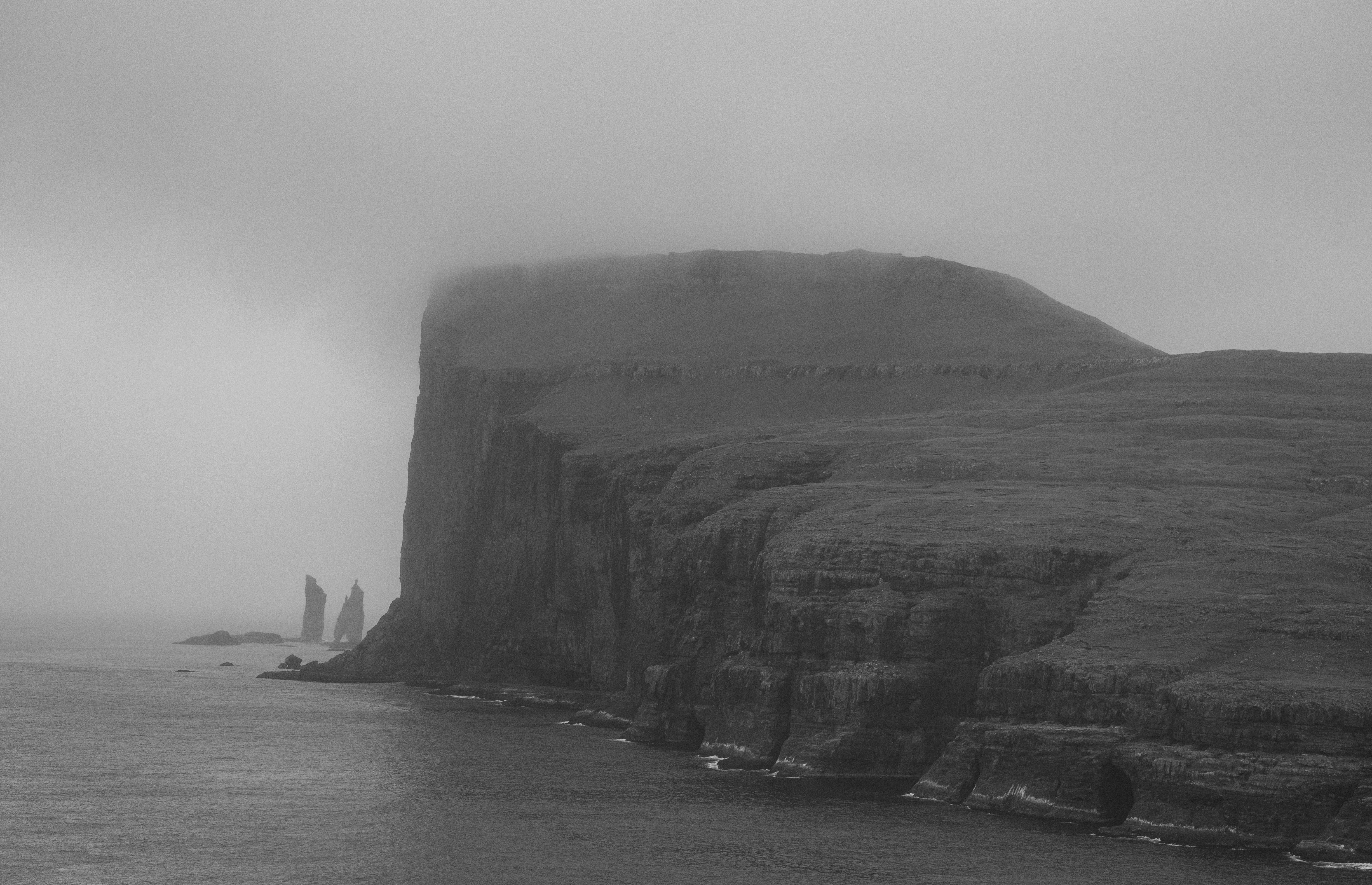 a black and white photo of a foggy coastline, 