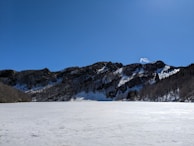 A wide shot of a frozen lake reflecting snowy peaks on a crisp winter day.