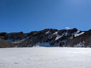Frozen lake surface reflecting the crisp winter sky with distant mountain silhouettes