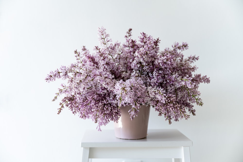 a white table topped with a vase filled with purple flowers