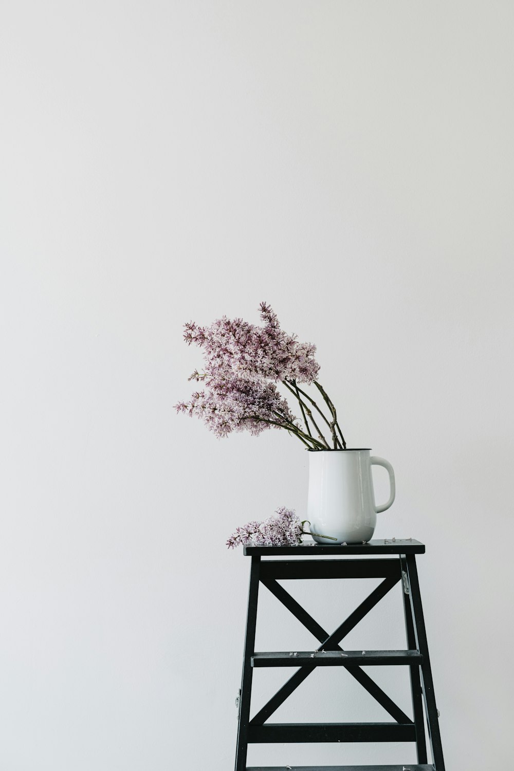 a white vase with some purple flowers in it