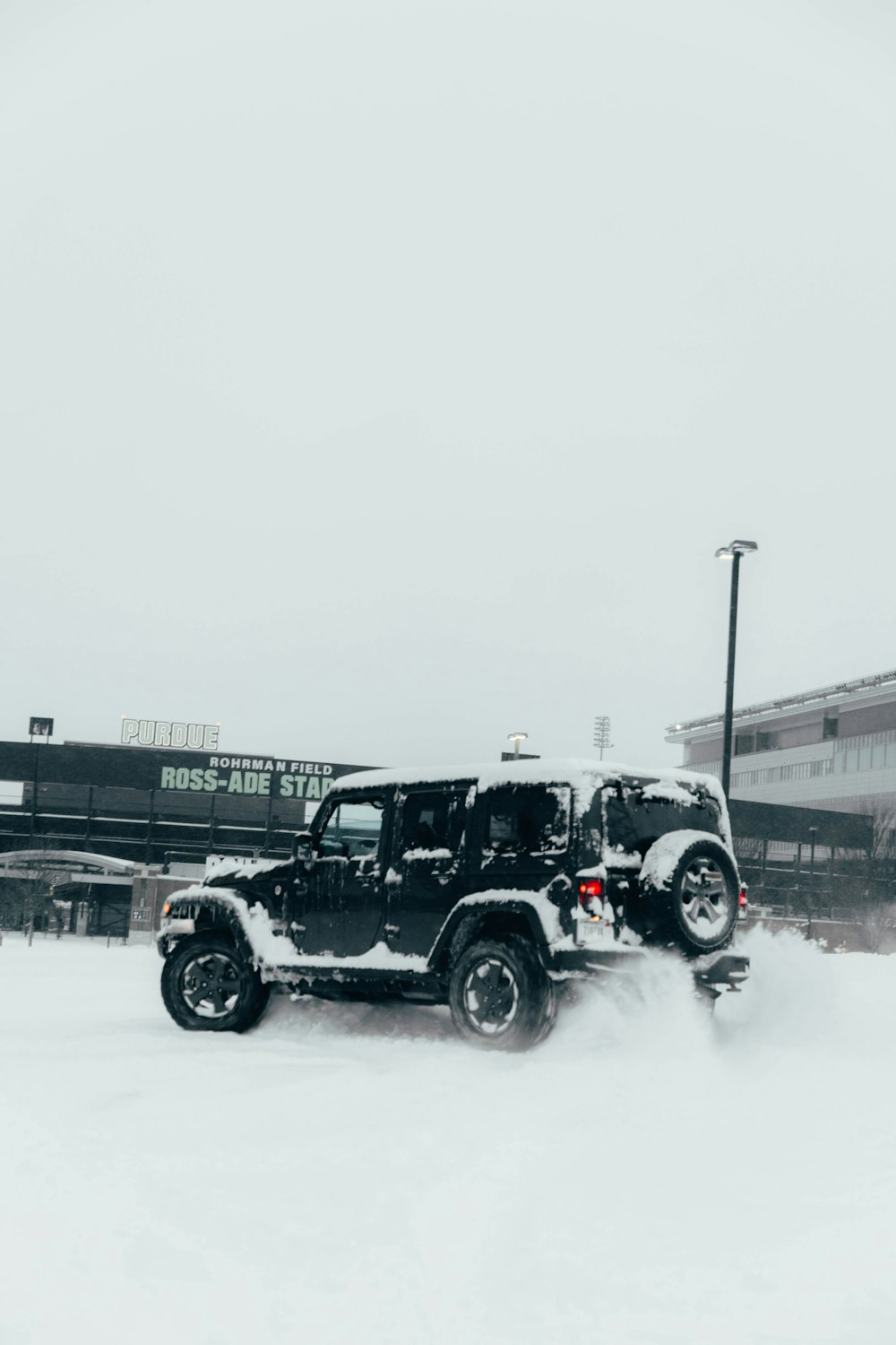 um jipe dirigindo através de um estacionamento coberto de neve