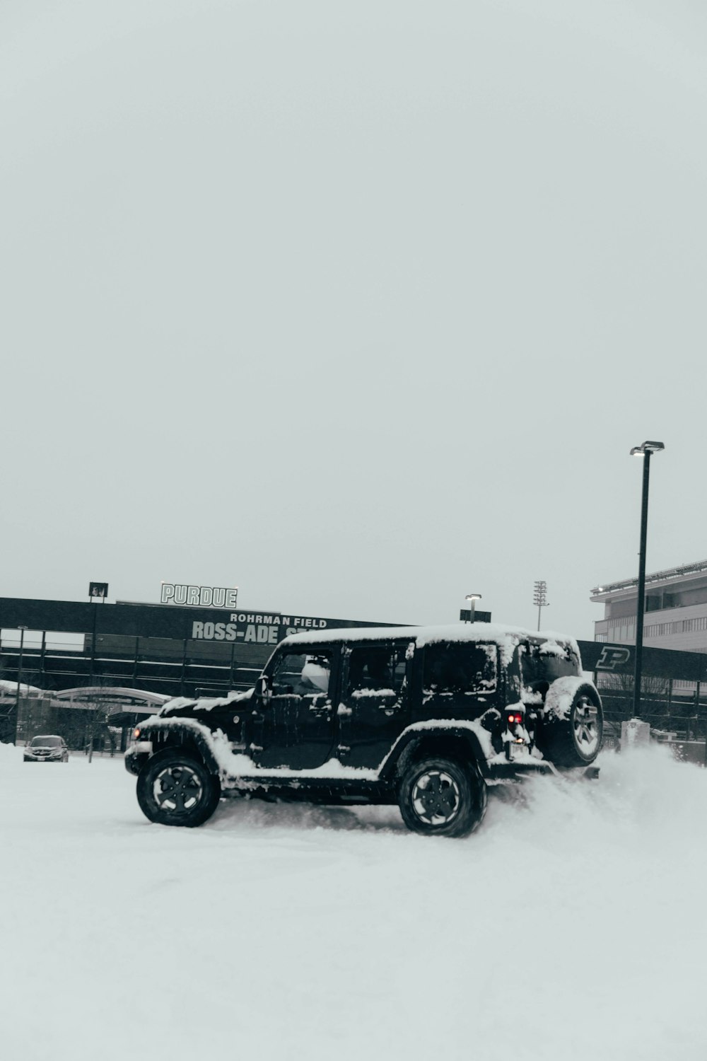 a jeep driving through a snow covered parking lot