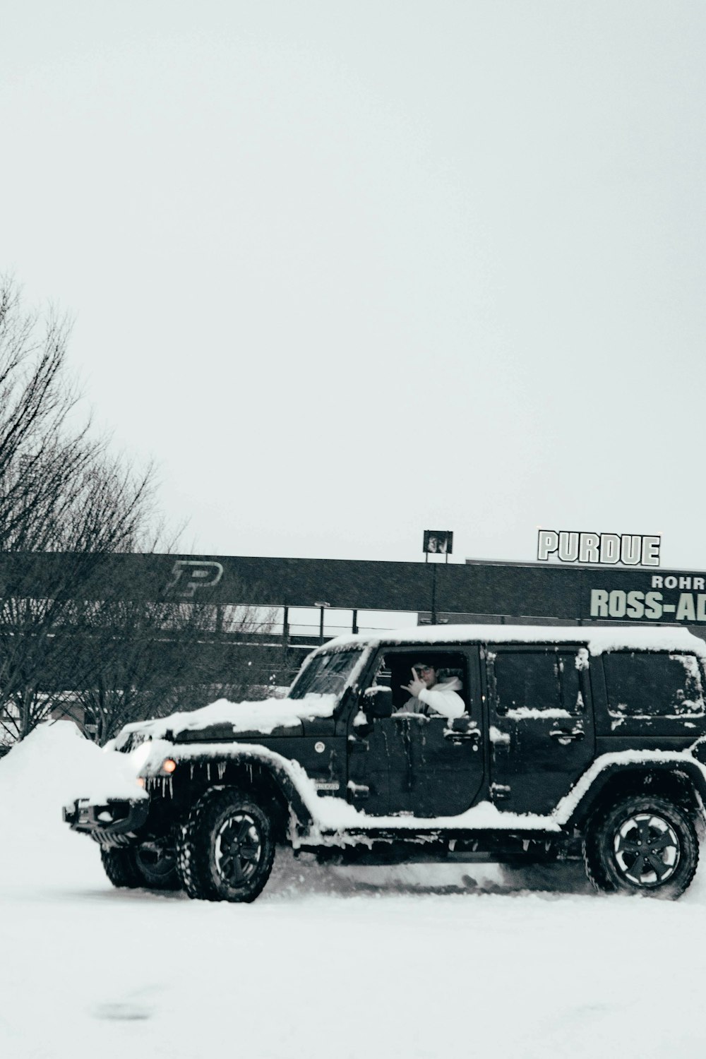 a jeep driving through a snow covered parking lot