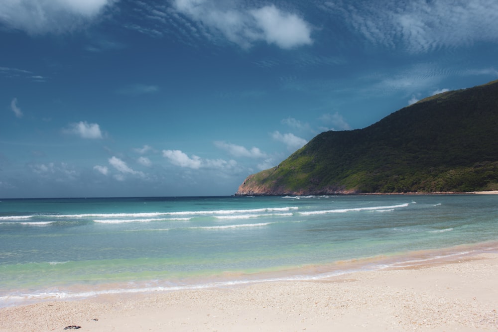 a sandy beach with a mountain in the background