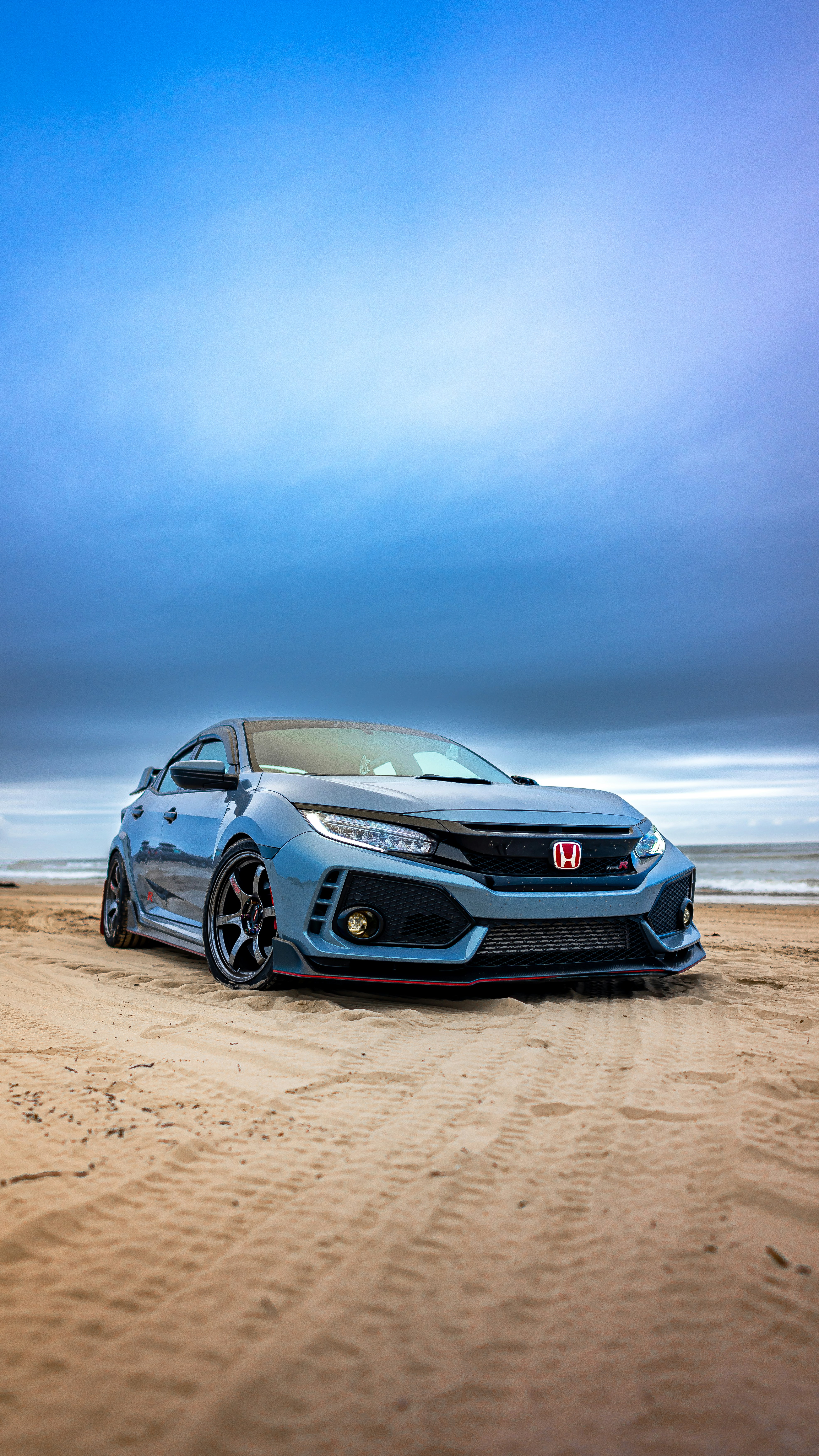 a silver car parked on top of a sandy beach
