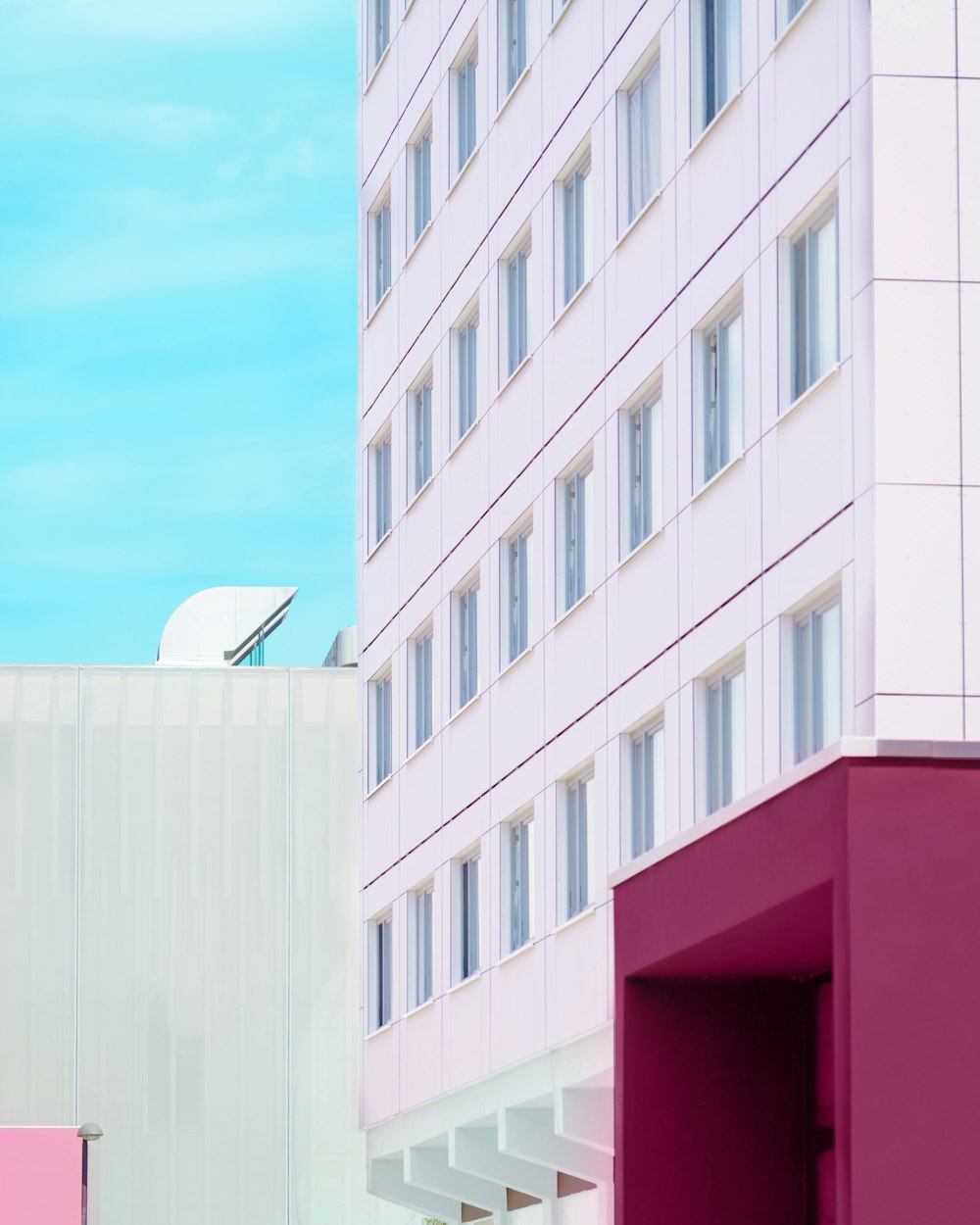 a tall white building sitting next to a tall pink building