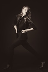 A vibrant photo of a model wearing a sleek, elegant outfit from the Naomi Eghaghe collection, standing confidently against a minimalist urban backdrop.