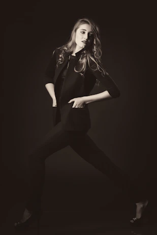 Model wearing a black timeless jacket against a muted celeste background, embodying elegant simplicity
