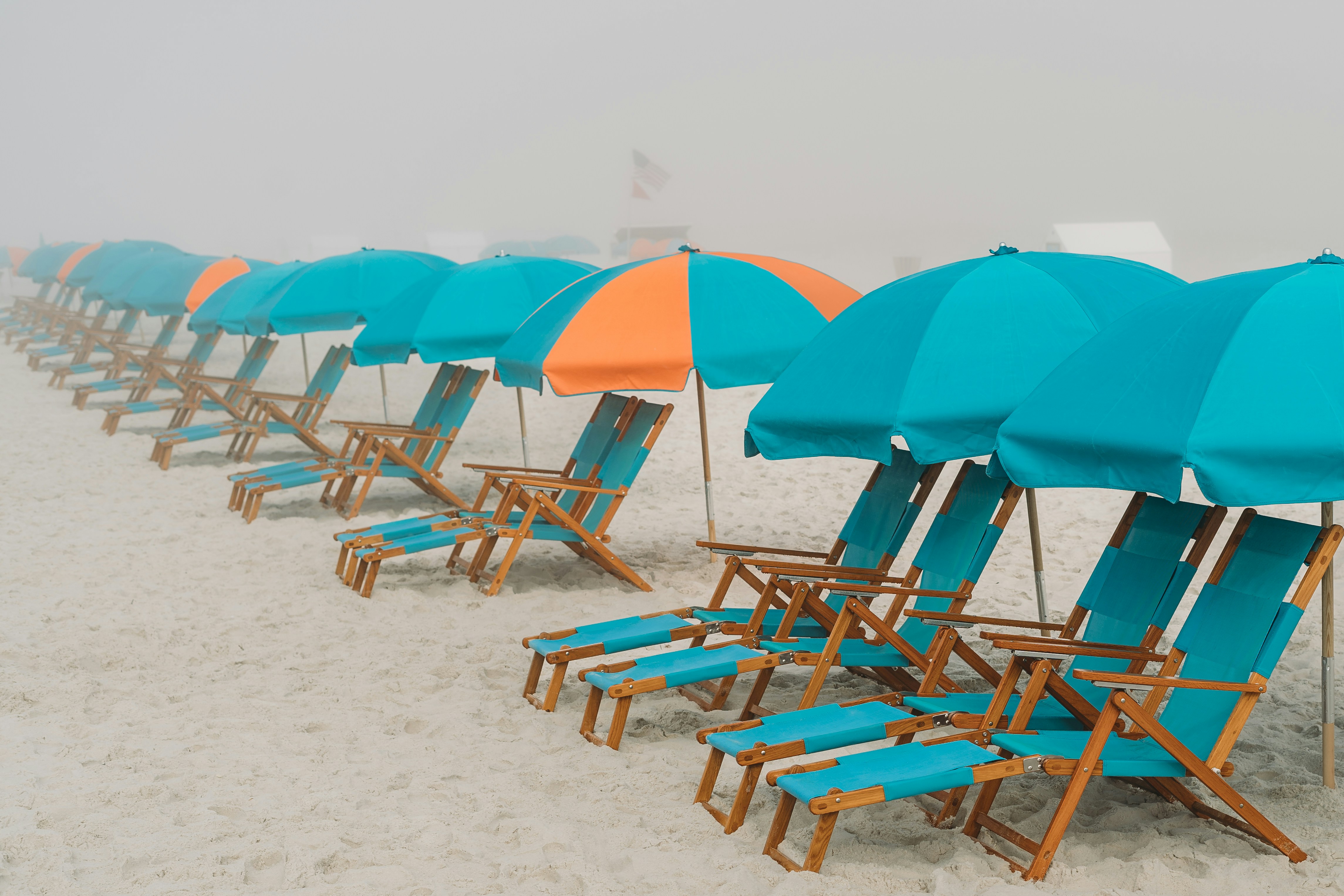 a row of beach chairs and umbrellas on a foggy day