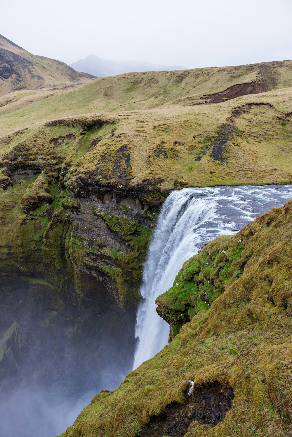 a waterfall in the middle of a grassy area