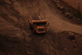 Trucks and equipment transporting materials on a rugged terrain.