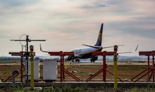 An airplane taxiing on the runway with cargo containers nearby.