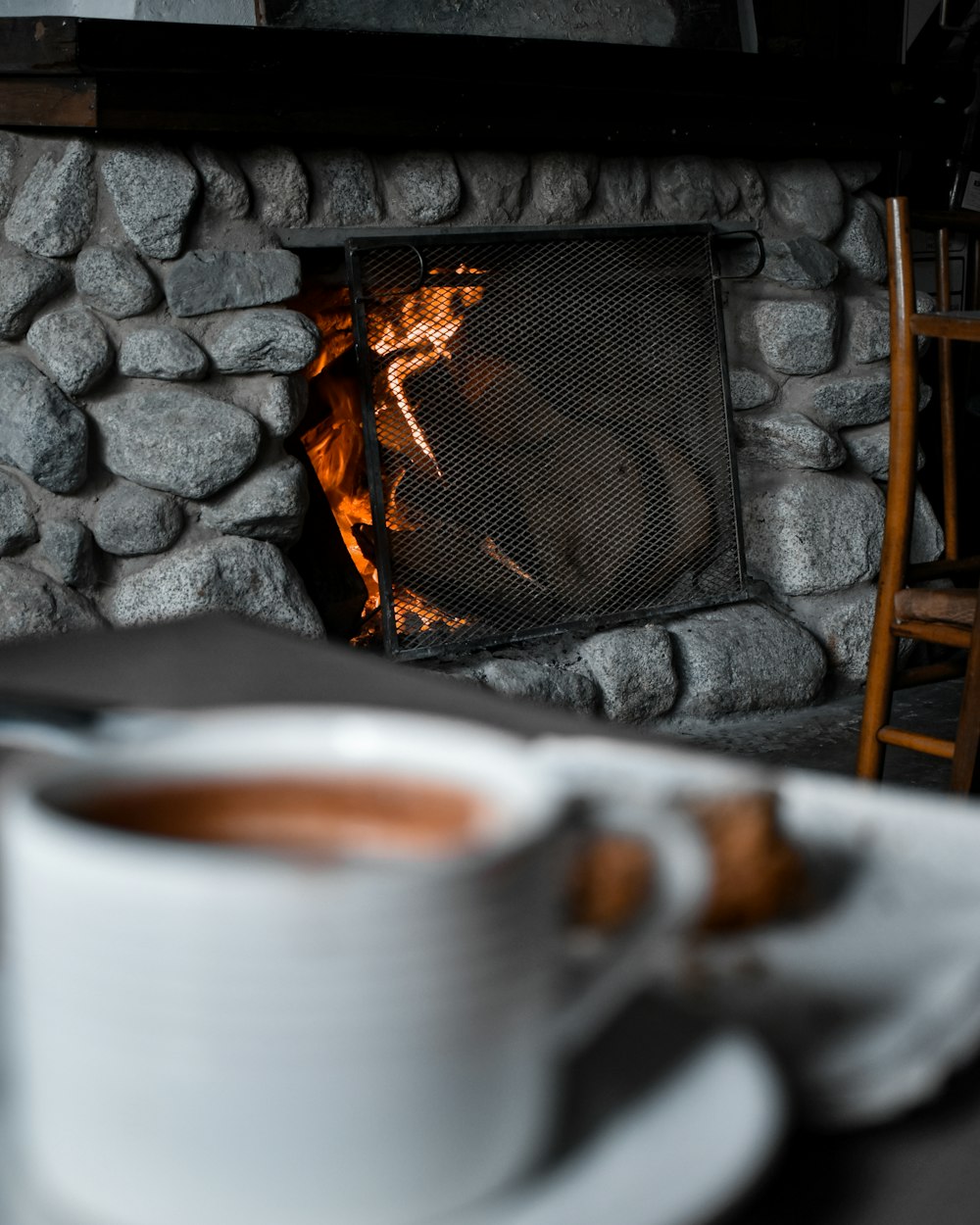 a cup of coffee sitting in front of a fire
