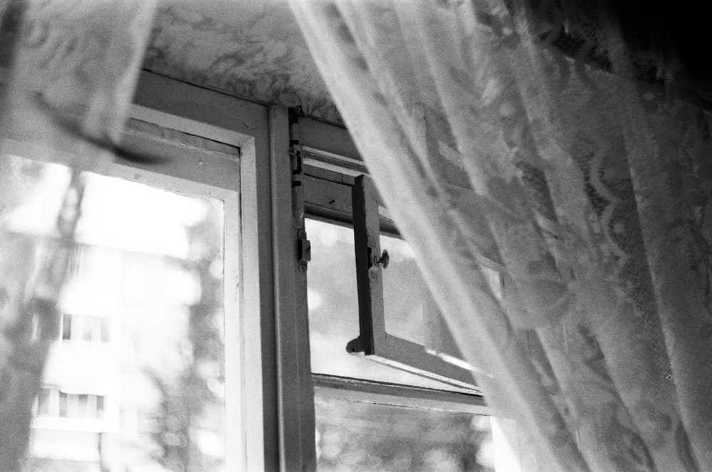 a black and white photo of a window with curtains