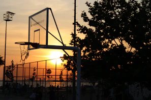 A sunset silhouette of kids shooting hoops together, embodying hope and community spirit