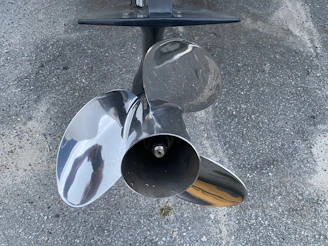 Close-up of shiny marine propellers and steering systems neatly arranged on white shelves.