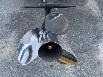 Close-up of shiny marine propellers and steering systems neatly arranged on white shelves.