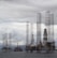 Several large offshore oil drilling platforms with tall lattice towers standing in the sea. The platforms are surrounded by a slightly cloudy sky.