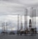 Several large offshore oil drilling platforms with tall lattice towers standing in the sea. The platforms are surrounded by a slightly cloudy sky.