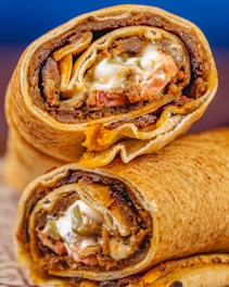 Close-up of a juicy shawarma wrap filled with seasoned meat and fresh vegetables.
