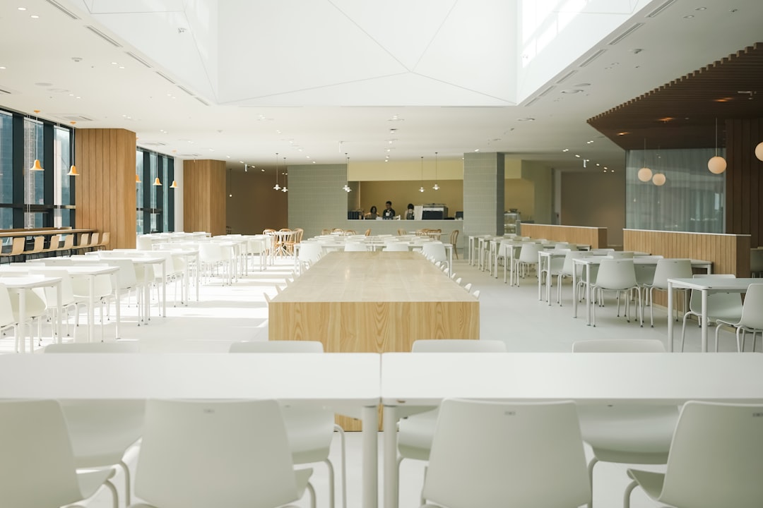 a large room with tables and white chairs,