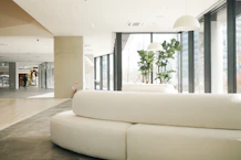 a white couch sitting in a living room next to a tall window