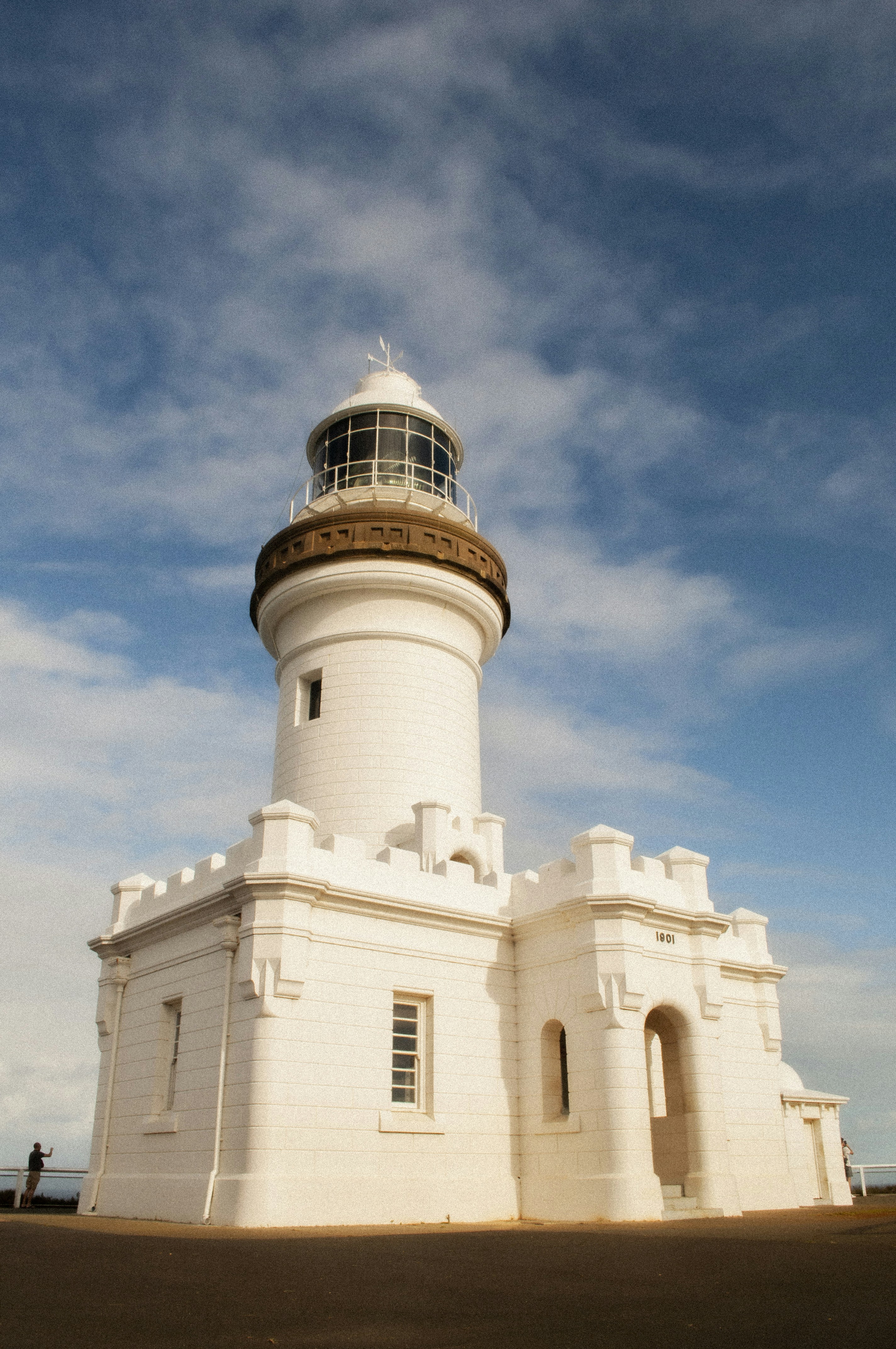 a white lighthouse with a brown top on a sunny day