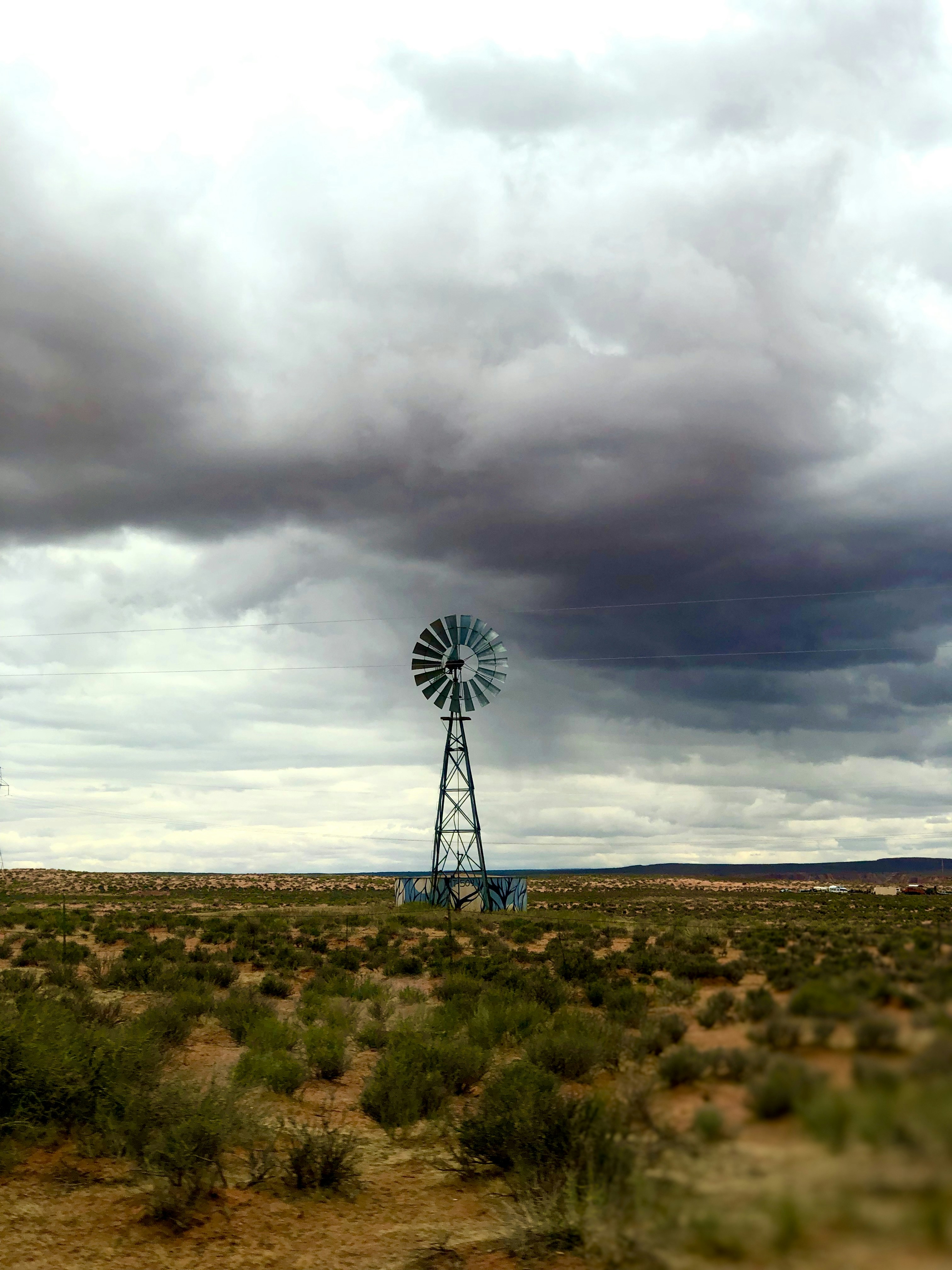 A windmill in the middle of a field under a cloudy sky photo – Free ...