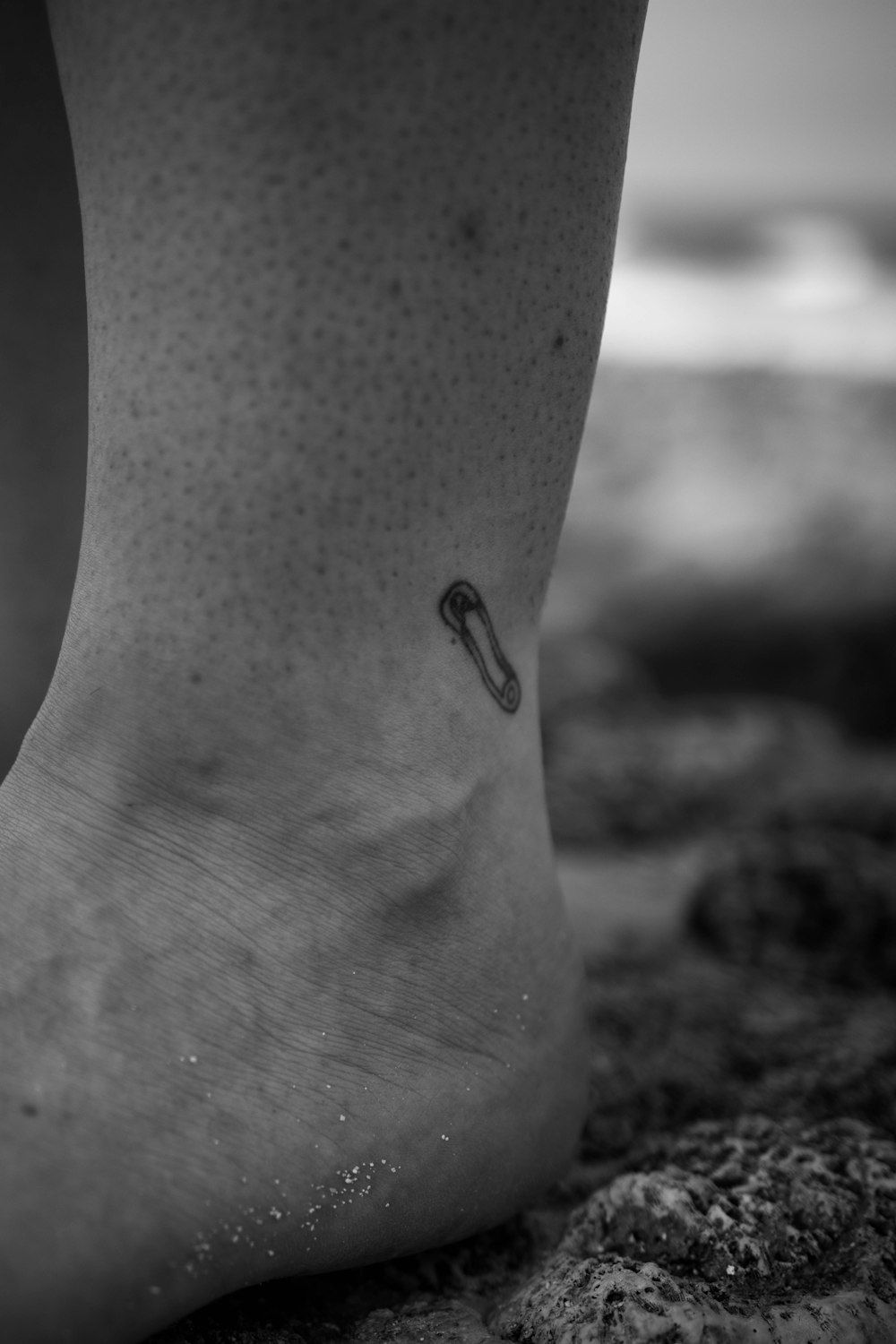 a black and white photo of a person's foot with a small umbrella tattoo