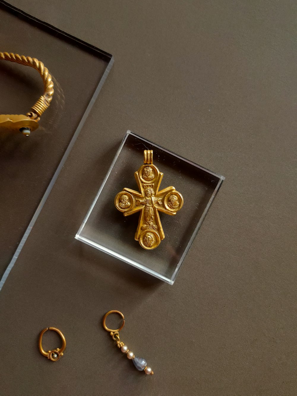 a pair of gold earrings and a gold cross pendant