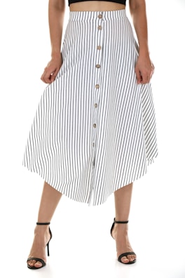 A person is wearing a vertically striped, button-down skirt with a black top. The skirt is white with black stripes and features several buttons down the front. The person is also wearing black high-heeled sandals.