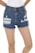 Blue denim shorts with frayed edges and distressed detailing. A white shirt is partially visible at the top, and bare legs are prominent in the image.