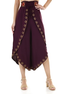 Stylish harem pants with a high waistband featuring a floral embroidered design in a contrasting color. The loose-fitting garment drapes elegantly, embellished with intricate patterns. A pair of beige sandals complements the outfit.