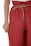 A close-up view of a person wearing loose-fitting red pants with a drawstring waistband. The pants have a crinkled texture, and the drawstring is made of a natural fiber material. The person’s hand is partially visible, resting on the side of the pants.