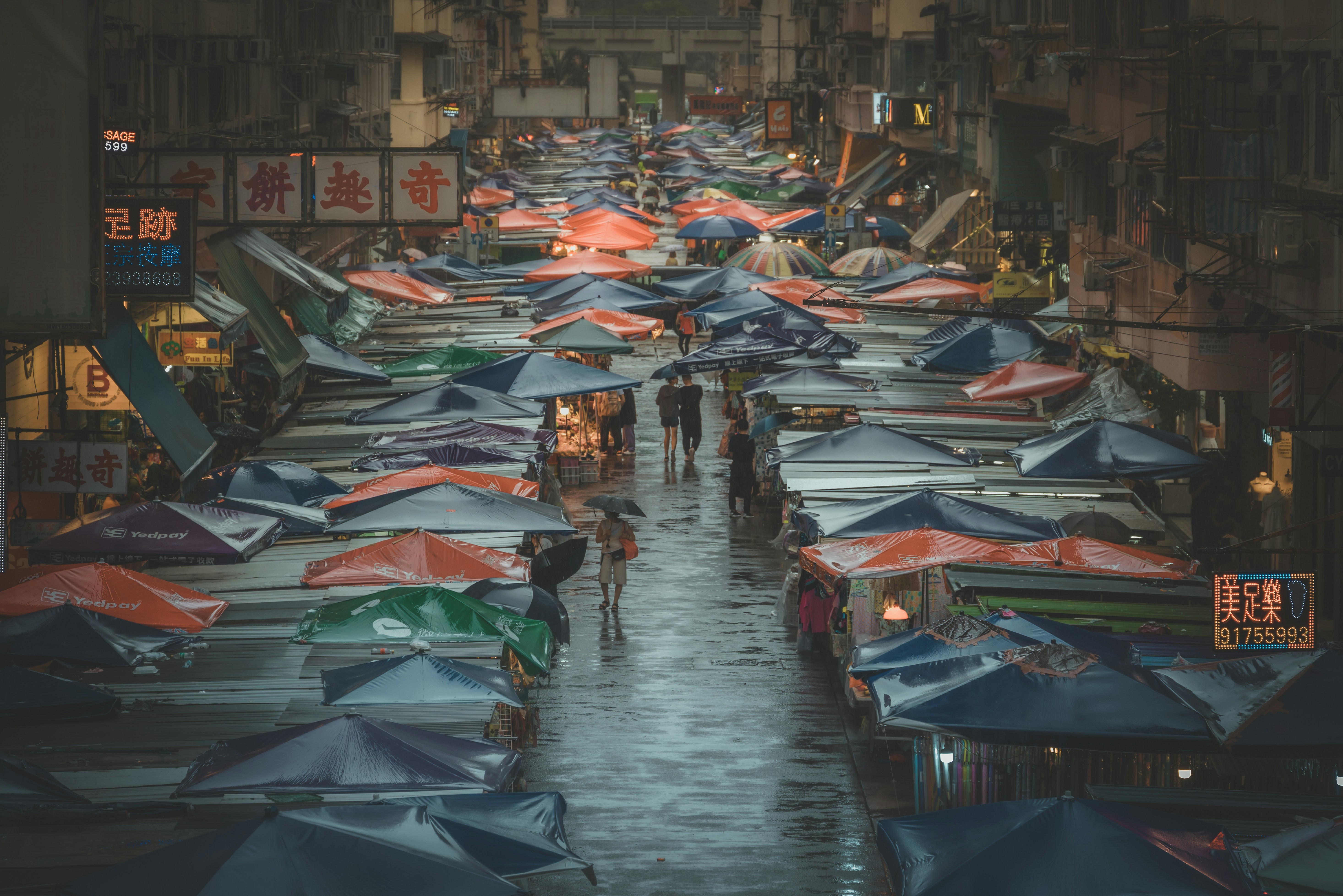 a group of people walking down a street holding umbrellas