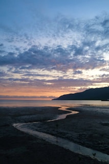 A serene landscape painting depicting a tranquil scene of the Portland coastline at sunset.
