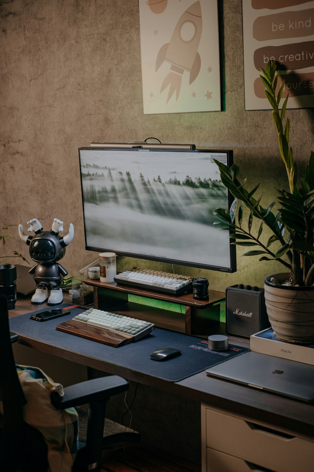 a desk with a computer and a plant on it