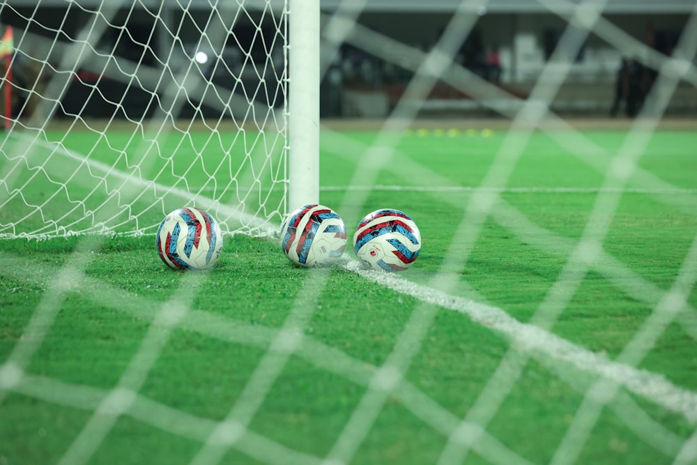 two soccer balls sitting on a soccer field